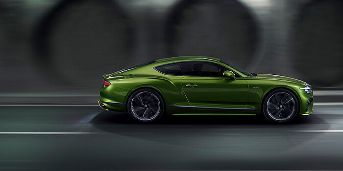  Bentley Glasgow Bentley Continental GT coupe in Tourmaline Green paint driving in profile on a dark road