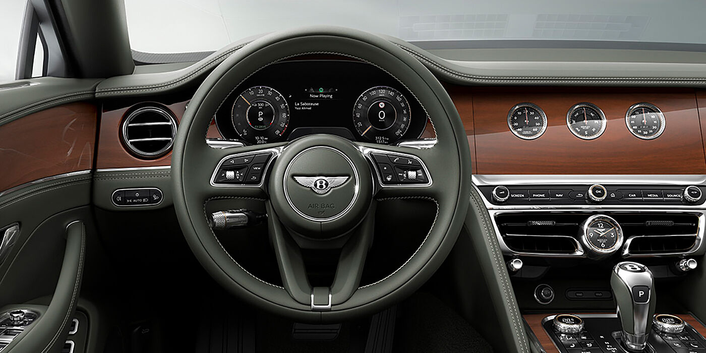 Bentley Glasgow New Bentley Flying Spur sedan front cabin in Cumbrian Green hide and Crown Cut walnut veneer showing steering wheel and Rotating Display with three clocks on face