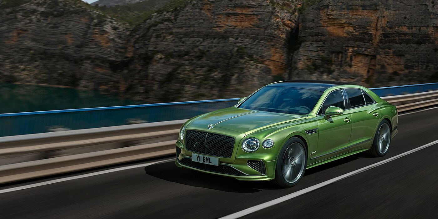 Bentley Glasgow Bentley New Flying Spur Speed v8 hybrid sedan driving dynamically on a mountain road in Tourmaline Green paint