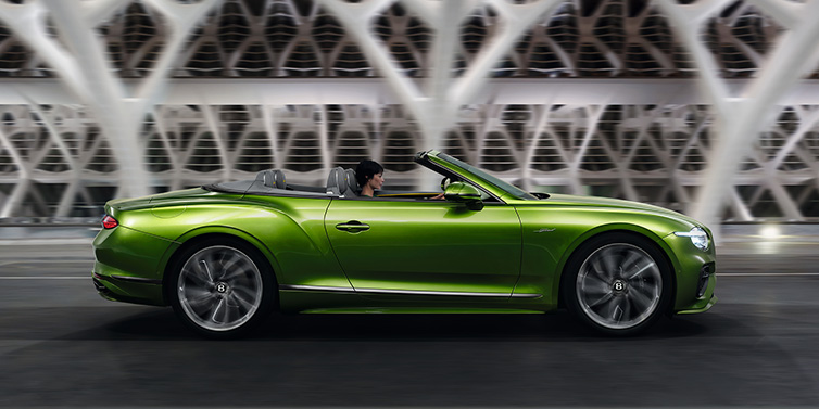 Bentley Glasgow Bentley Continental GTC Speed convertible side profile in Tourmaline Green paint driving dynamically on a bridge at night