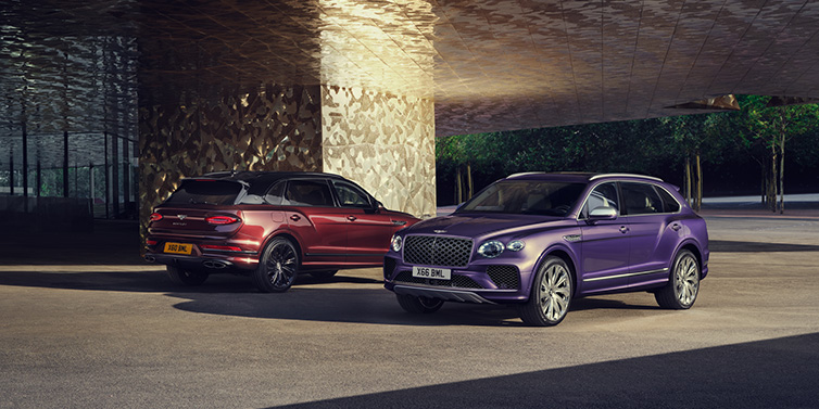 Bentley Glasgow A duo of Bentley Bentayga Extended Wheelbase Mulliner SUVs parked in a city environment, with Tanzanite Purple and Cricket Ball red exterior paint