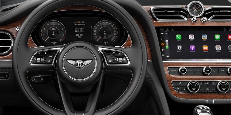 Bentley Glasgow Bentley Bentayga SUV front interior detail of steering wheel and driver screens surrounded by Beluga black hide and Crown Cut Walnut veneer